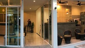 A modern interior with a glass door entrance, a kitchen area with a counter and chairs, and a ceiling fan. - Capricorn Village (Patong)