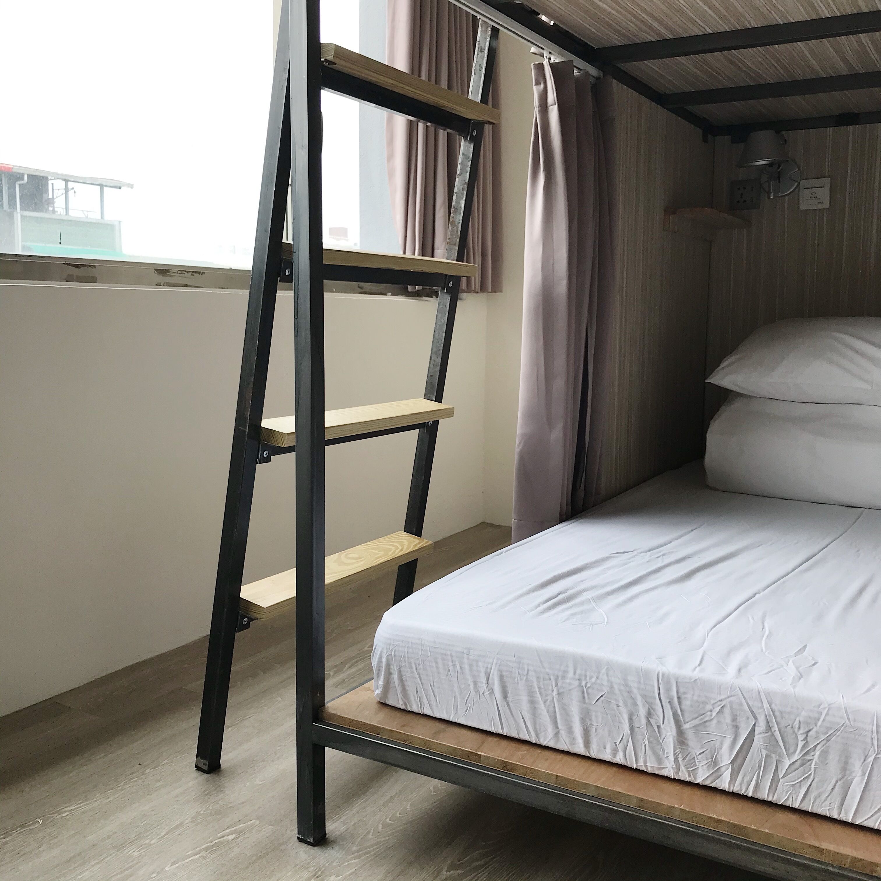 A bunk bed with a ladder, a window with curtains, and a bed with white bedding.