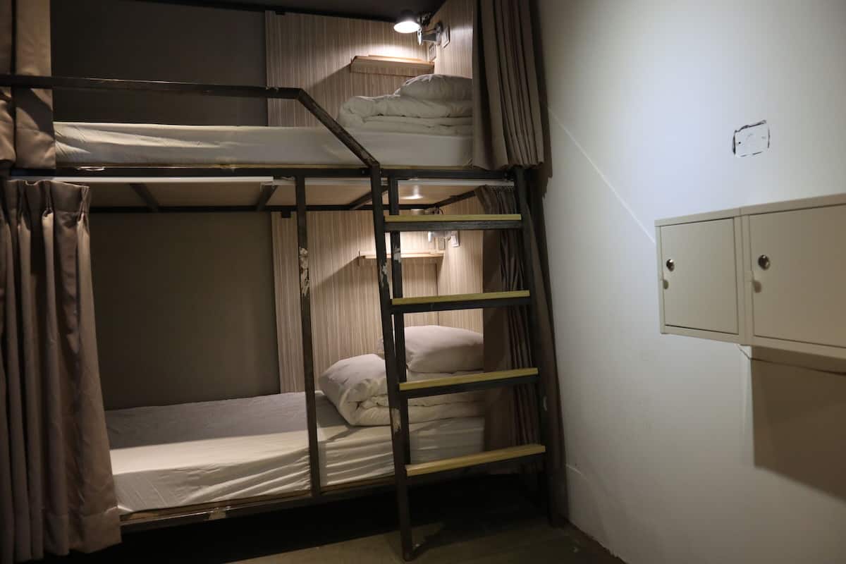 A bunk bed room with a ladder, a small desk, and a cabinet.