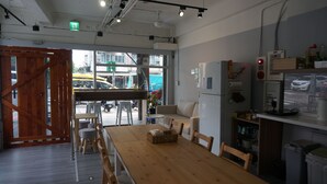 Um interior moderno com uma mesa de jantar de madeira, cadeiras, uma geladeira e uma vista através de amplas janelas.