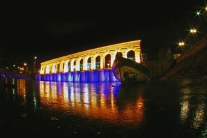 Un puente iluminado con arcos y un mural lateral, visible de noche.