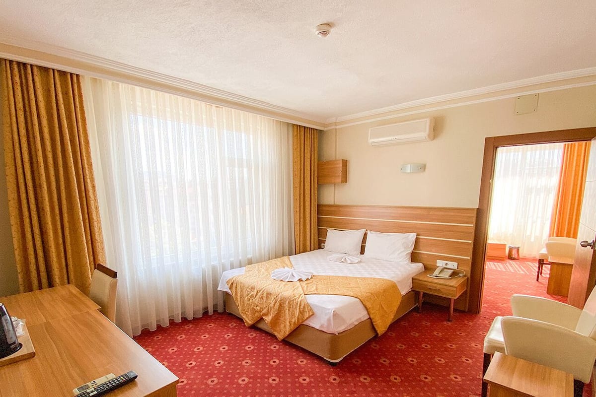 A hotel room with a bed, bedside table, chair, and a desk with a chair.