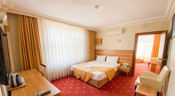 Una habitación de hotel con cama, mesita de noche, silla y escritorio con otra silla.