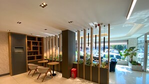 Un interior moderno con una zona de estar, una estantería y vista al estacionamiento.