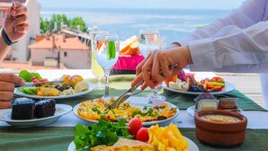 Una mesa dispuesta con diferentes platos, vasos de agua y vistas al mar.