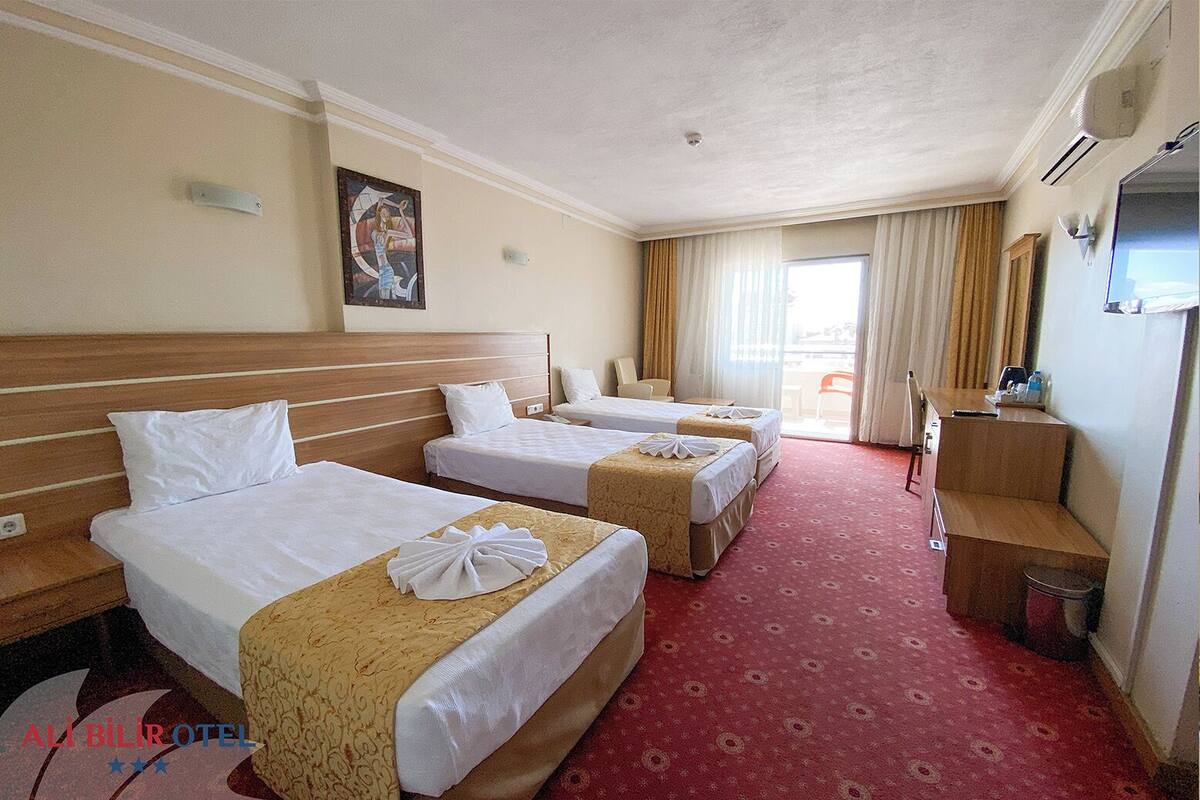 A hotel room with three beds, a desk, and a chair.