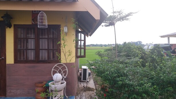 A house with a yellow facade, a brown door, and a window with a wooden frame. - 7 Up Resort (Nakhon Nayok)