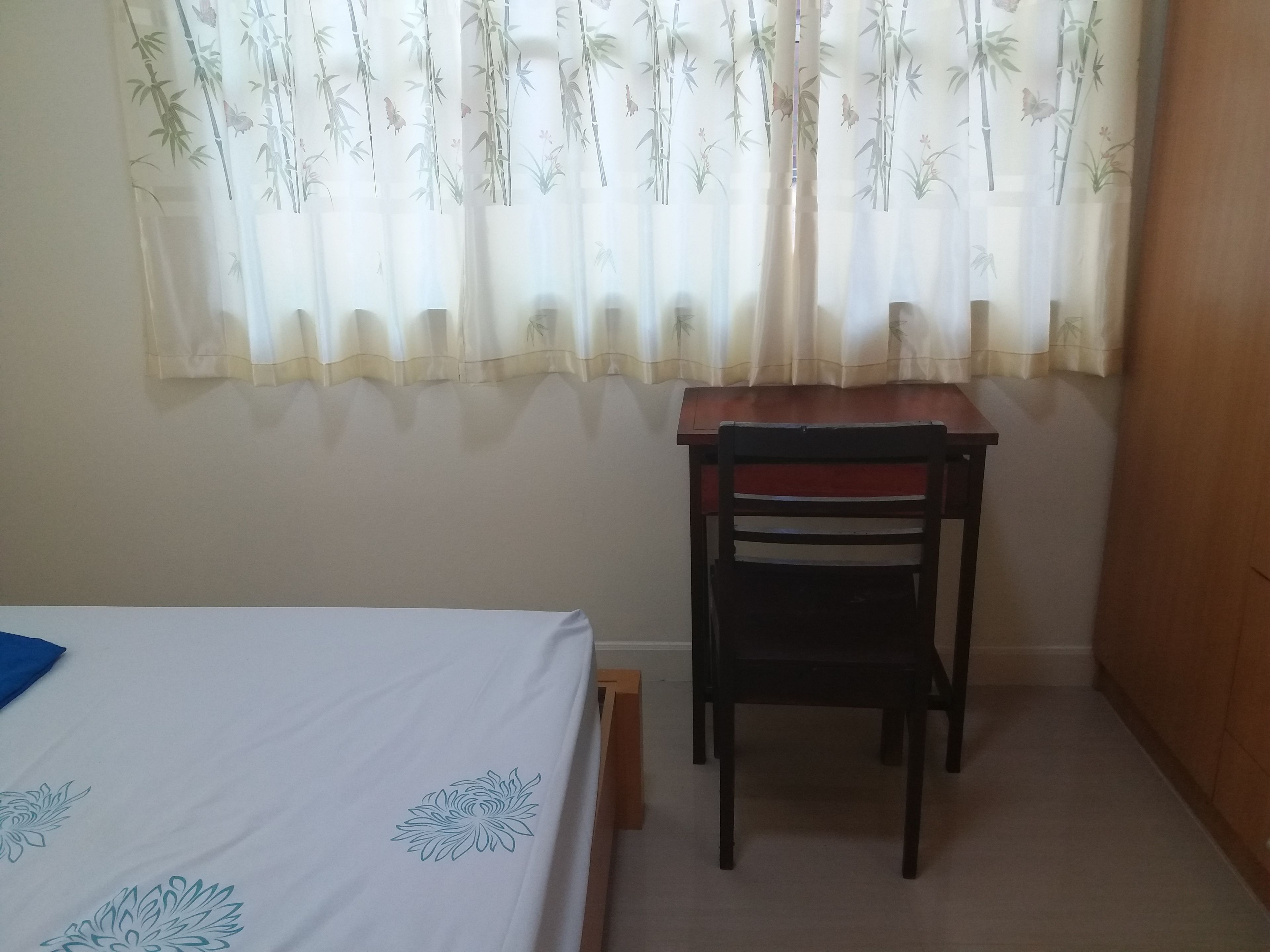 Um quarto com uma cama, uma escrivaninha de madeira e uma cadeira.