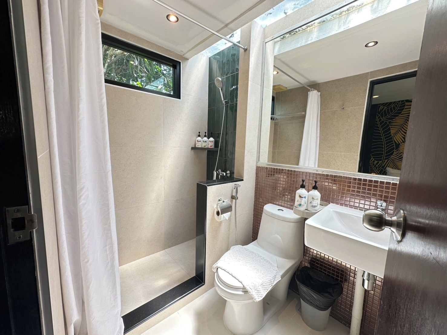 A compact bathroom with a shower, toilet, and sink.