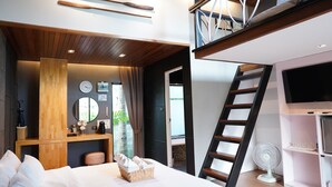 Een moderne hotelkamer met een bed, een houten bureau, een ventilator en een televisie.