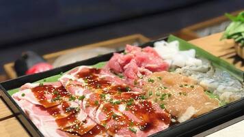 Uma bandeja com fatias variadas de peixe e carne cruas, decorada com sementes de gergelim e cebolinha.