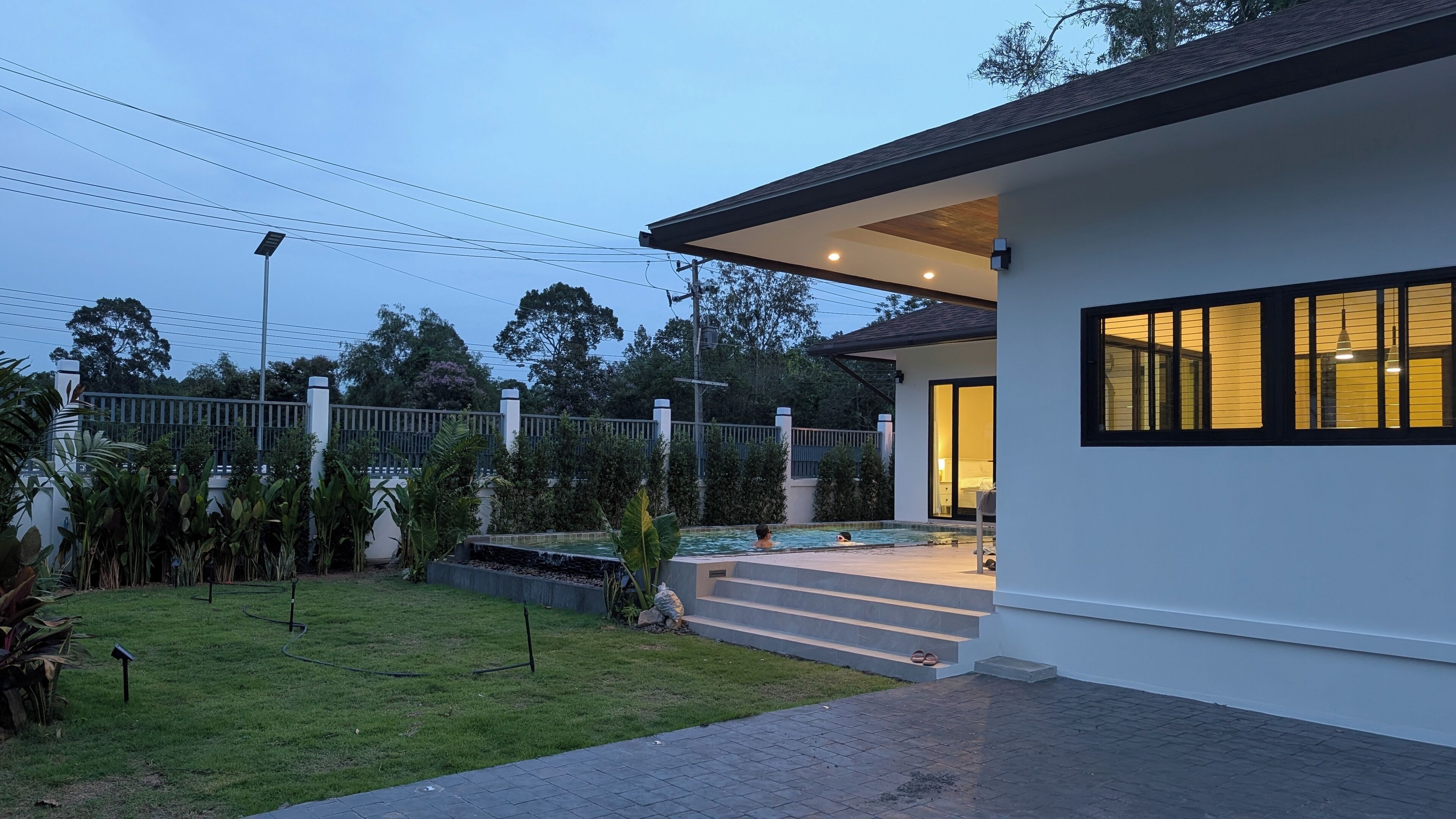 A modern house with a swimming pool, a covered patio, and a well-maintained garden.