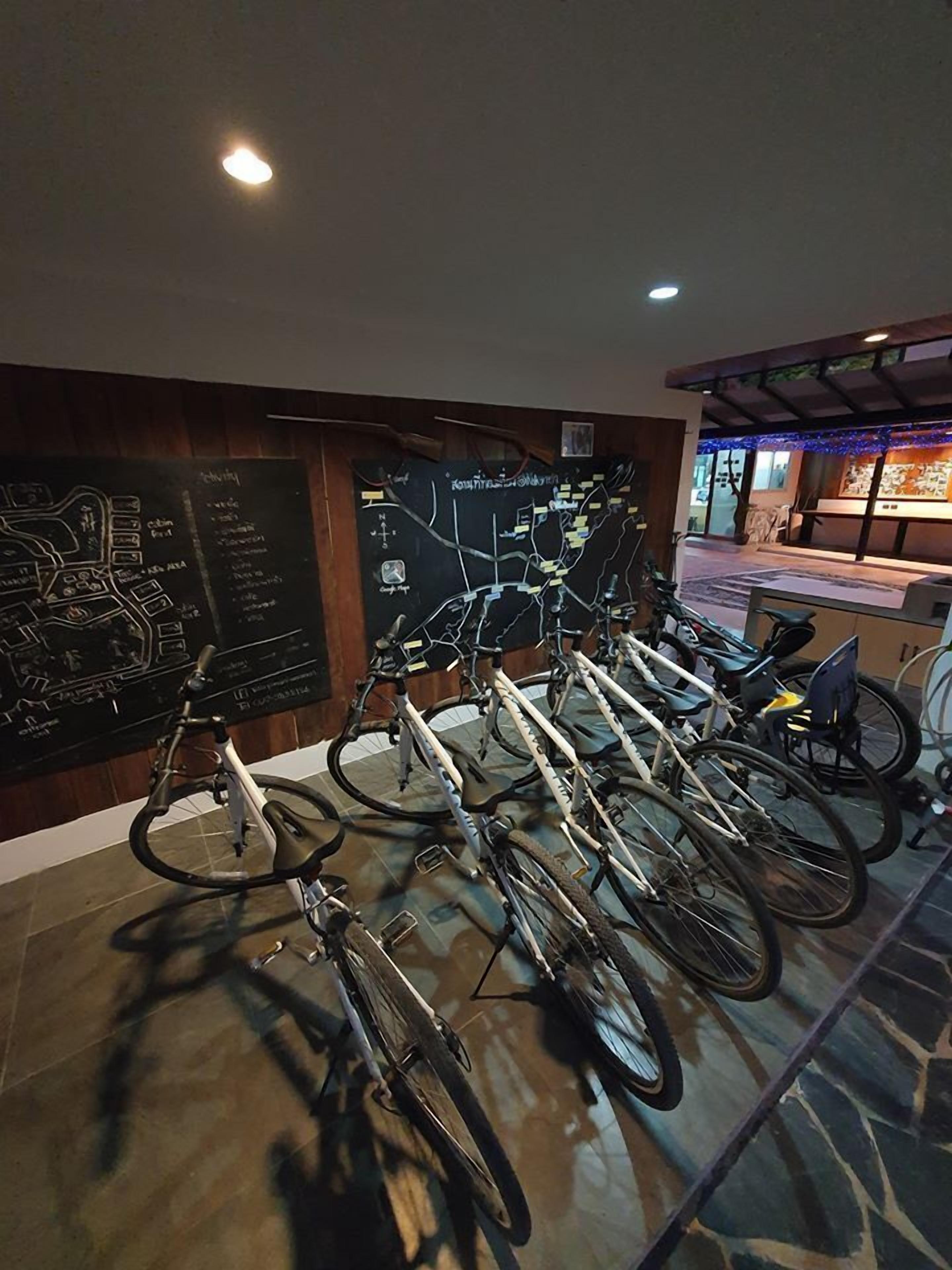 A row of bicycles parked against a wall with a map and a sign listing amenities.