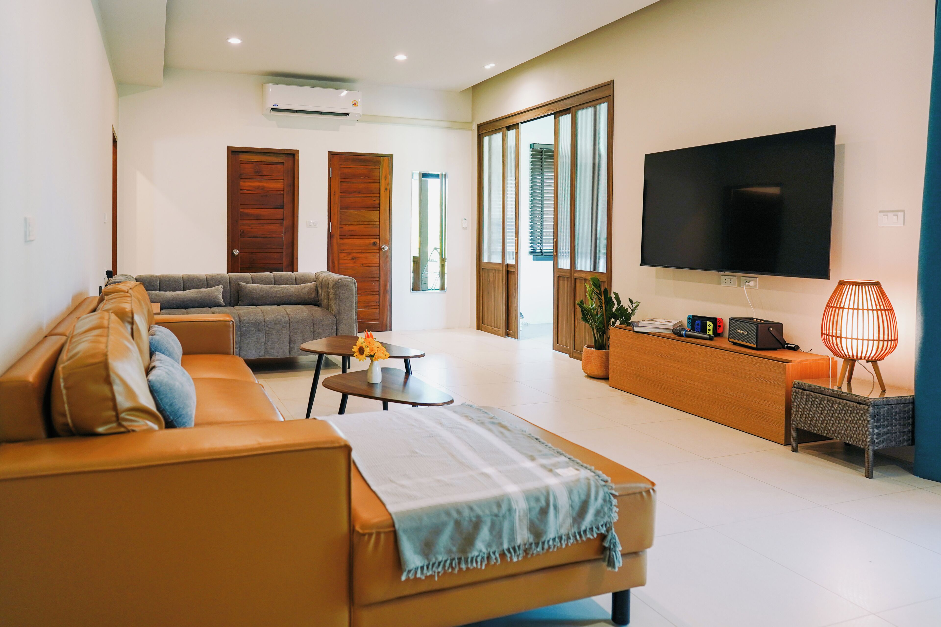 Una sala de estar con un sofá, una mesa de centro, un televisor y una lámpara.