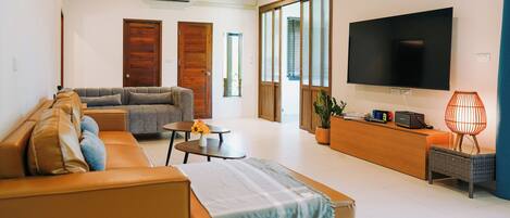 Una sala de estar con un sofá, una mesa de centro, un televisor y una lámpara.