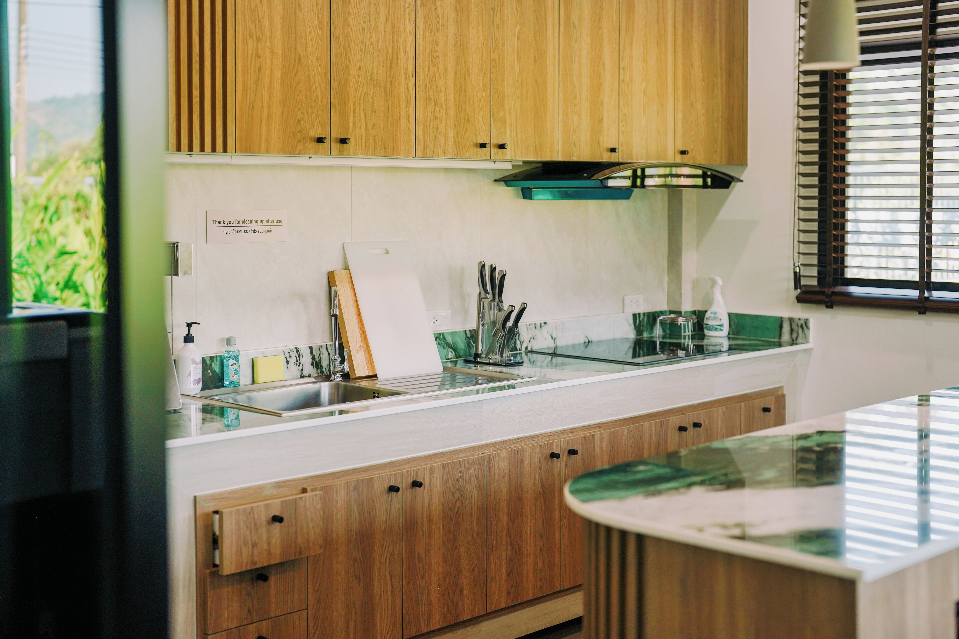 A modern kitchen with wooden cabinets, a glass backsplash, and a stainless steel sink.