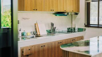 A modern kitchen with wooden cabinets, a glass backsplash, and a stainless steel sink.