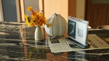 A table with a vase of flowers, a modern tablet, and a newspaper.