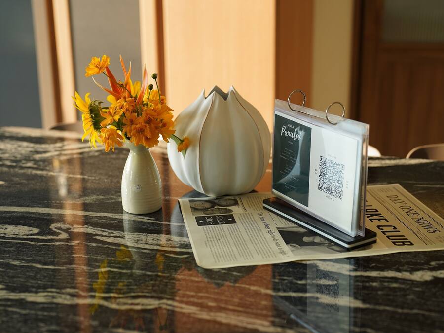 A table with a vase of flowers, a modern tablet, and a newspaper.
