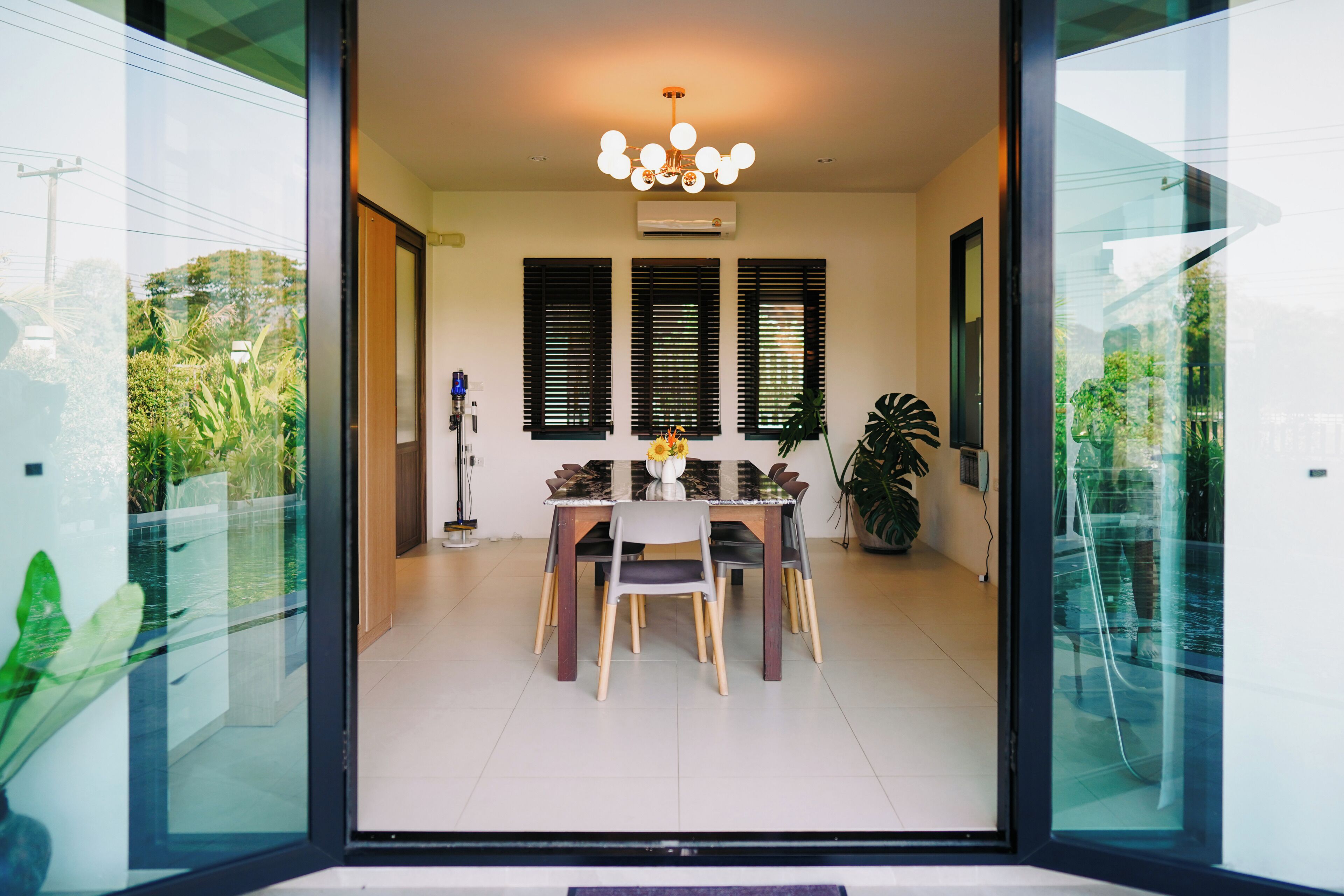 A modern dining area with a glass partition, a chandelier, and a dining table with chairs.