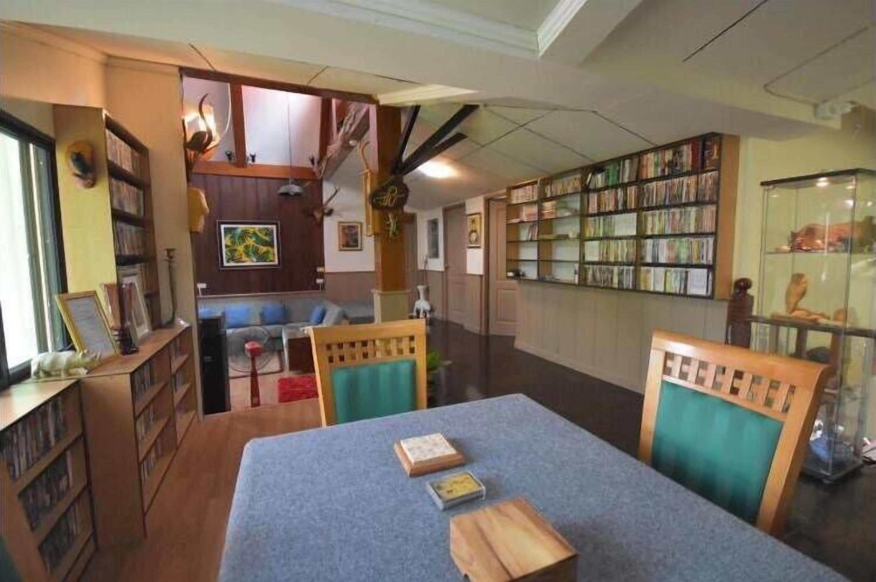 A library with bookshelves, a reading area with chairs, and a table with books.