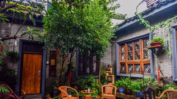 A courtyard with traditional wooden furniture, potted plants, and a large tree. - Suzhou Yard (Suzhou)