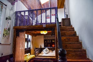 A traditional wooden staircase leading to a bedroom with a bed, a small table, and a shelf with decorative items. - Suzhou Yard (Suzhou)
