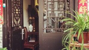 A traditional Chinese gate with intricate lattice design, a white vase with flowers, and a potted plant. - Suzhou Yard (Suzhou)