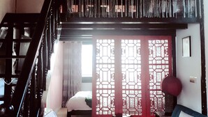 A living room with a staircase, a sofa, a small table, and a decorative hanging. - Suzhou Yard (Suzhou)