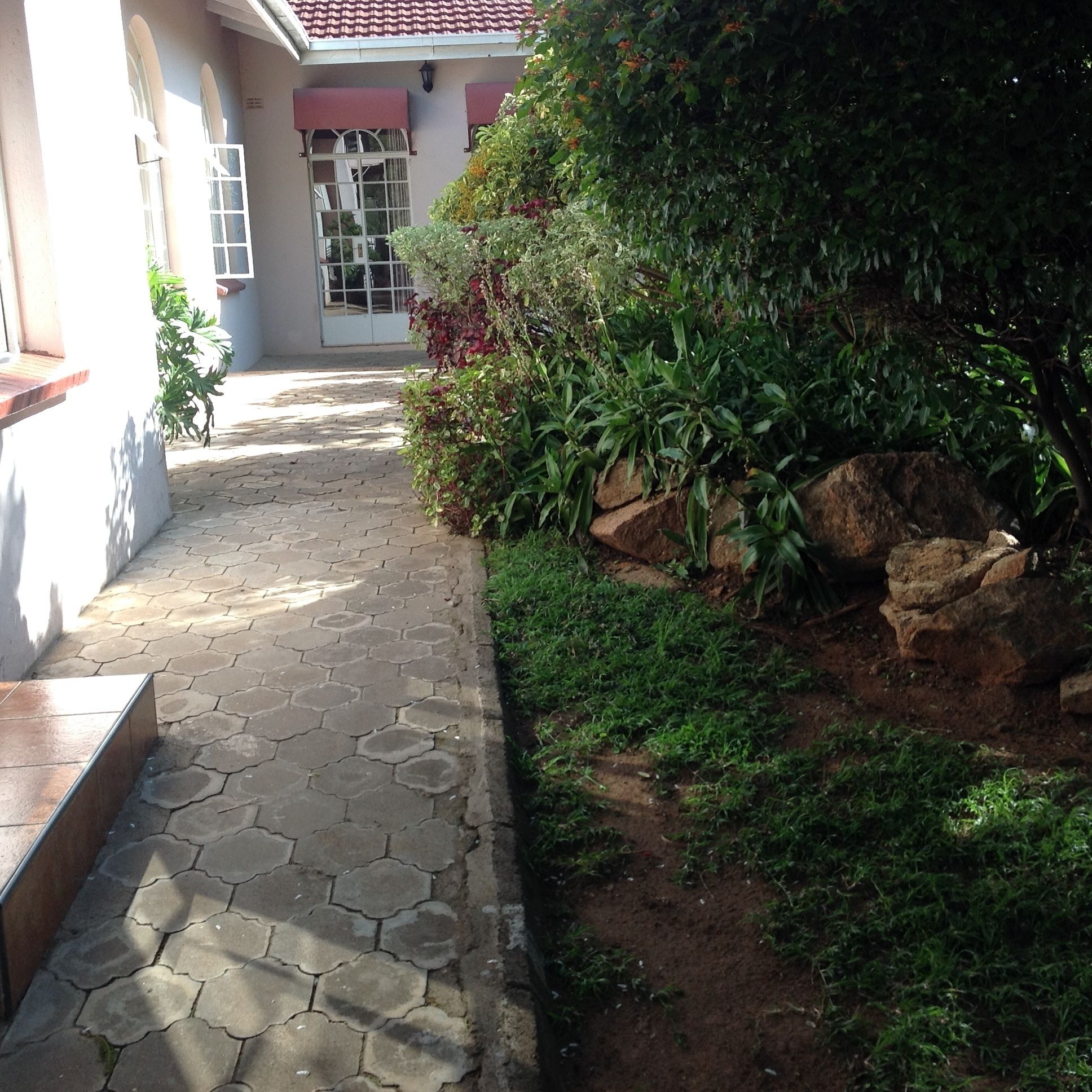 A paved pathway leading to a building with a tiled roof and a door with glass panels.