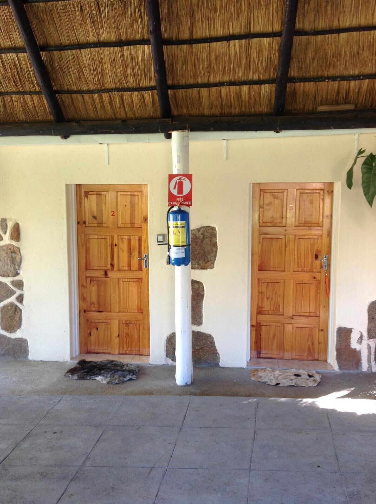 A building entrance with two wooden doors, a fire extinguisher, and a sign indicating a fire exit.