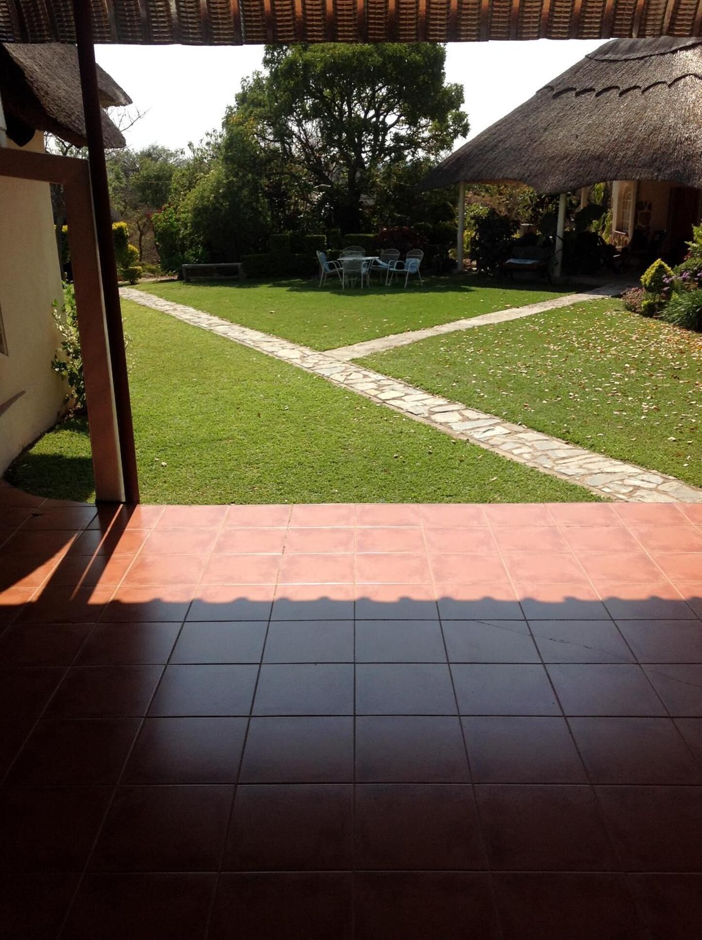 Un'area patio con pavimento piastrellato che conduce a un prato con un vialetto in pietra.