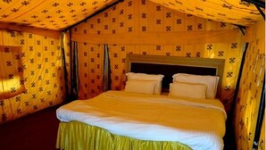 A tent-style room with a bed, curtains, and a patterned wall. - TIH Royal Desert Camp (Leh)