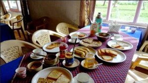 A dining table with various dishes and drinks, surrounded by chairs. - TIH Royal Desert Camp (Leh)
