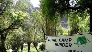 A sign for Royal Camp Hunder in Nibra, surrounded by trees and a stone wall. - TIH Royal Desert Camp (Leh)