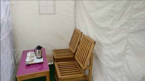 A small room with a wooden bench, a table with a kettle, and a green mat. - TIH Ladakh Summer Camp Pangong (Leh)