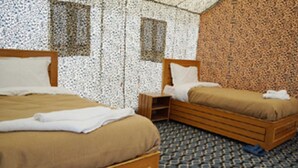 A bedroom with two wooden beds, a patterned carpet, and a small wooden nightstand. - TIH Ladakh Summer Camp Pangong (Leh)