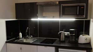 Une cuisine compacte équipée d’un four à micro-ondes, d’une machine à café, d’un grille-pain et d’un évier.