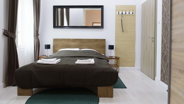 Une chambre bien rangée, avec un grand lit, des lampes de chevet, un miroir et une armoire.