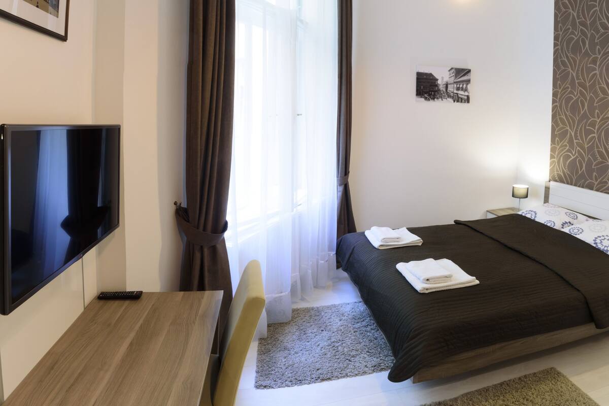 Ein Hotelzimmer mit Bett, Fernseher, Schreibtisch und Stuhl.
