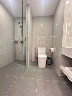 Un baño moderno con ducha de vidrio, inodoro y basurero.