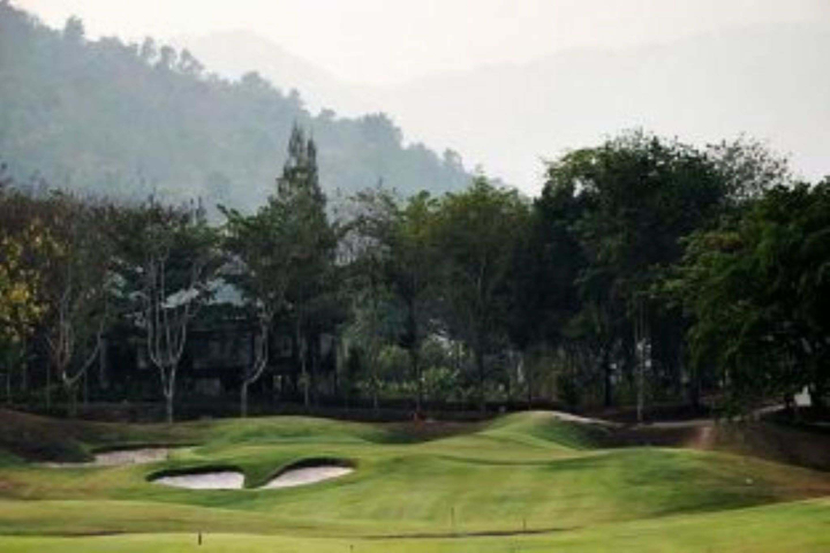 A golf course with sand bunkers and trees.
