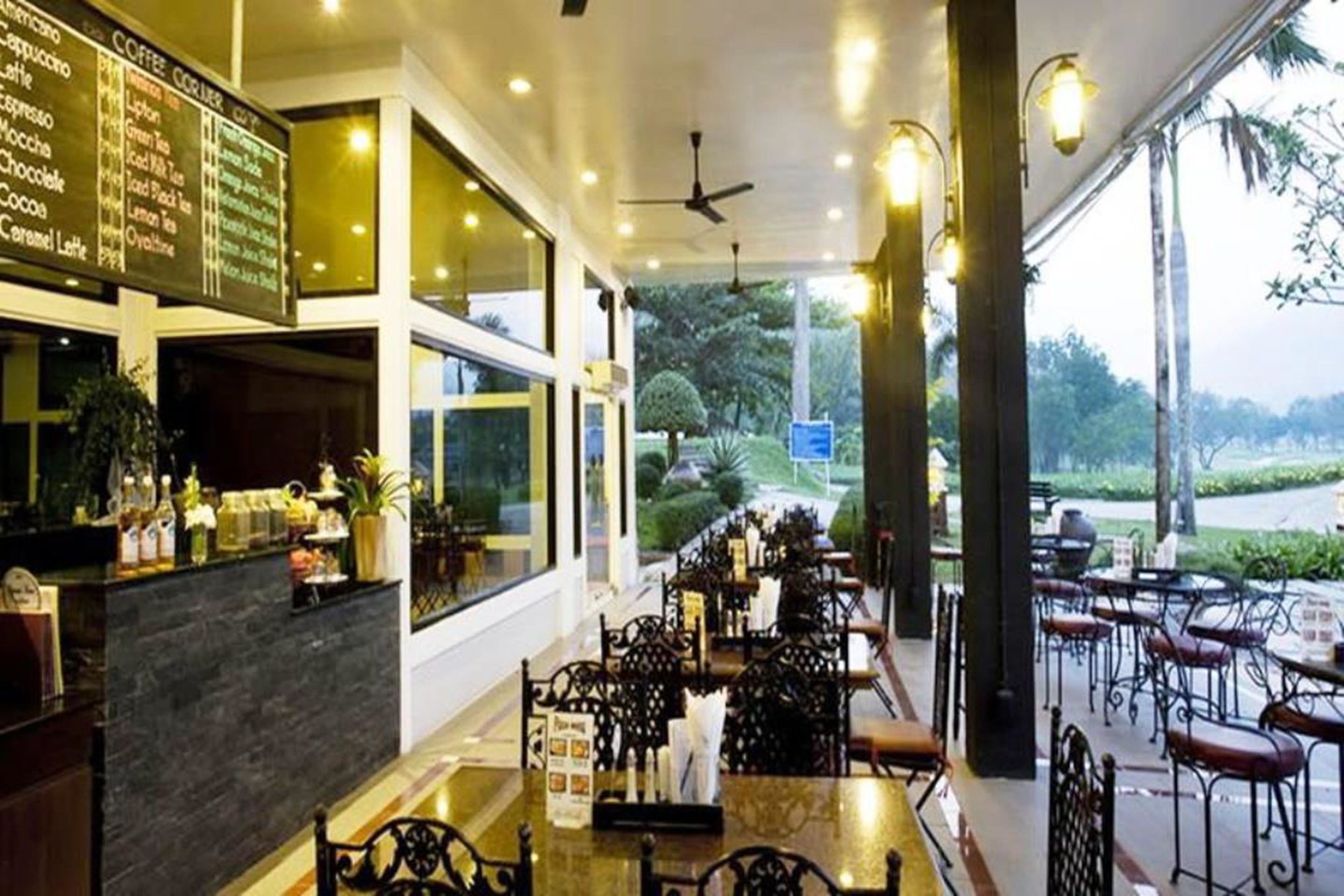 An indoor cafe with a menu board, tables, chairs, and a view of the outdoors.
