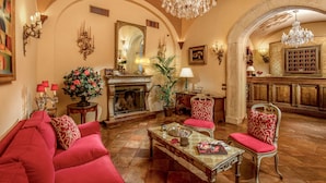 A luxurious living room with a fireplace, red upholstered furniture, and ornate chandeliers. - Boutique Hotel Campo dé Fiori (Rome)