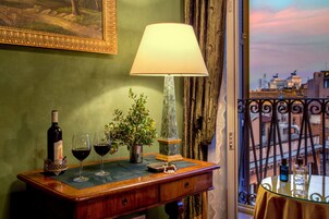 Angolo bar con una bottiglia di vino, due bicchieri da vino, una pianta in vaso, una lampada e vista sulla città attraverso una finestra.