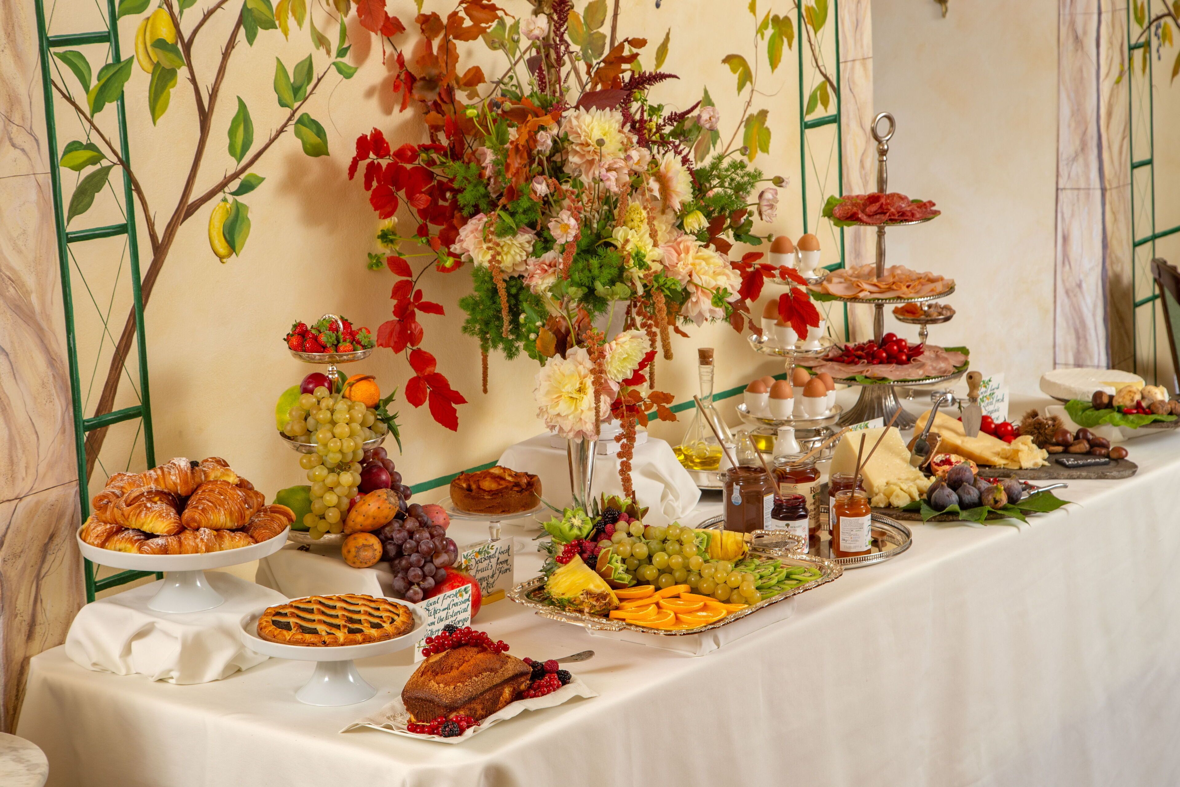 A buffet table with various food items and a decorative floral arrangement.