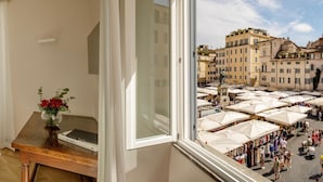 A room with a large window overlooking a bustling outdoor market with numerous white umbrellas and people. - Boutique Hotel Campo dé Fiori (Rome)