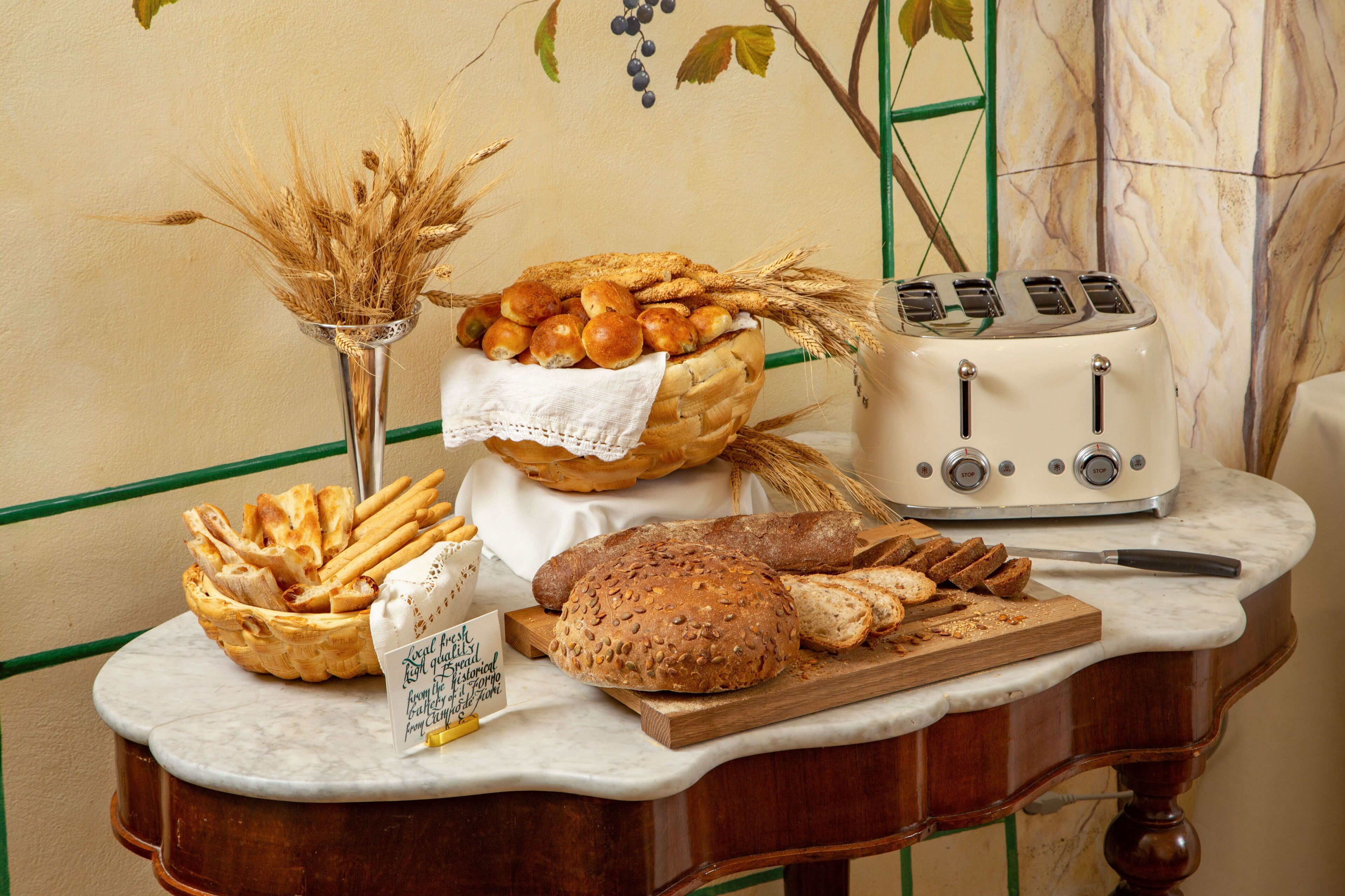 A table with various breads, a toaster, and a cutting board with bread slices.