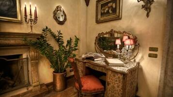 Ein stilvolles Zimmer im Vintage-Look mit Kamin, Schreibtisch mit Spiegel und einer Topfpflanze.