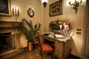 Una stanza in stile vintage con un camino, una scrivania con uno specchio e una pianta in vaso.